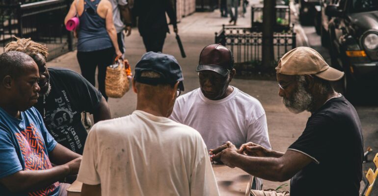 men sitting beside table on pathway near people walking beside rail